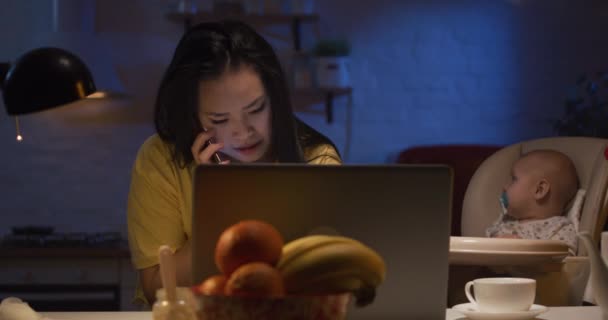 Jeune mère avec bébé travaillant sur un ordinateur portable — Video