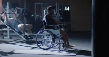 Wheelchair man sitting while others working out