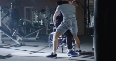 Trainer lifting disabled man into wheelchair