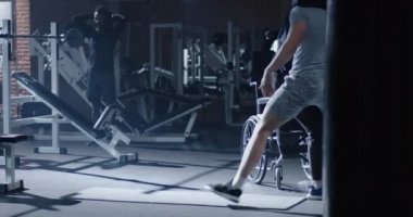 Trainer lifting disabled man into wheelchair