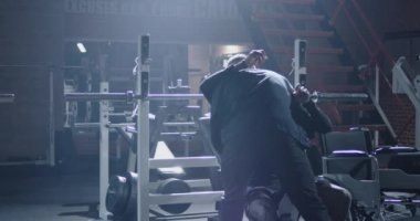 Trainer lifting disabled man onto training bench