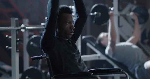 Homem cadeira de rodas levantando peso no ginásio — Vídeo de Stock