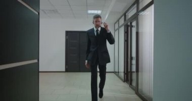 İş adamı ofis koridorunda kulaklıkla arıyor.