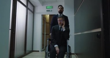 Tekerlekli sandalye yöneticisi ofis koridorundan arıyor.
