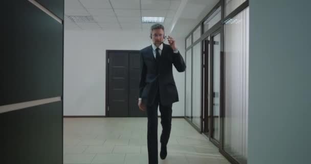 Businessman phoning with headset in office corridor — Stock Video