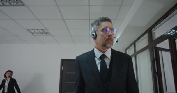 Zakenman belt met headset in kantoorgang — Stockvideo