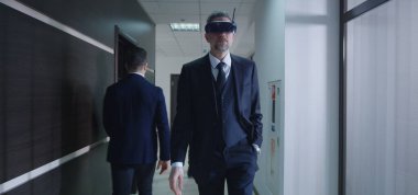 İş adamı ofis koridorunda VR gözlüğü kullanıyor.