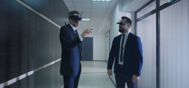 İş adamları ofis koridorunda VR gözlüğü kullanıyor.