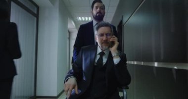 Tekerlekli sandalye yöneticisi ofis koridorundan arıyor.