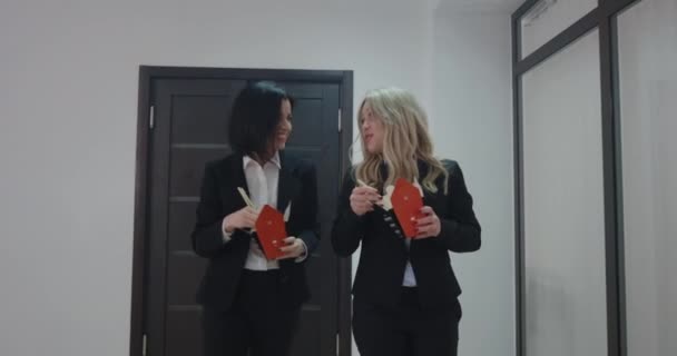 Ділові жінки спілкуються і їдять в офісному коридорі — стокове відео