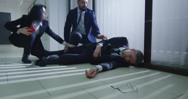 Compañeros ayudando a gerente inconsciente en la oficina — Vídeos de Stock