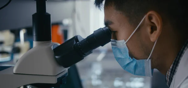 Wetenschapper die steekproef in microscoop bestudeert — Stockfoto