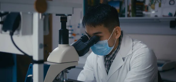 Scientist studying sample in microscope