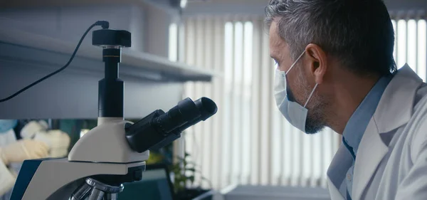 Forskare studerar prov i mikroskop — Stockfoto