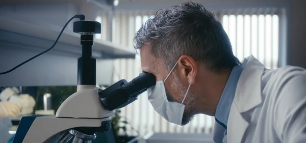 Científico estudiando muestra en microscopio —  Fotos de Stock