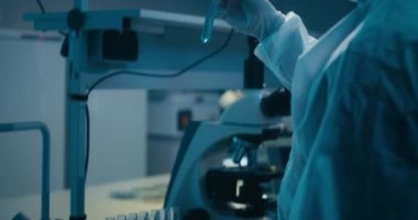 Bilimadamı laboratuvarda numune inceliyor.