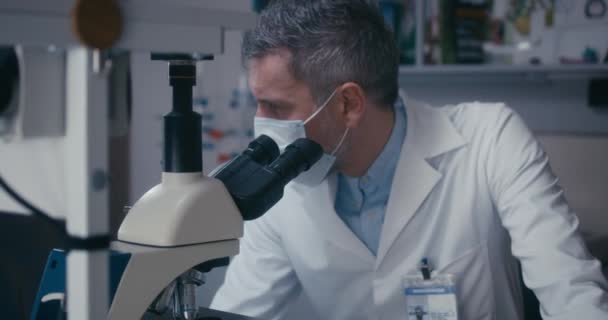 Científico estudiando muestra en microscopio — Vídeo de stock