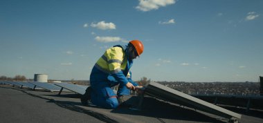 Teknisyen güneş paneli kuruyor ve kameraya bakıyor