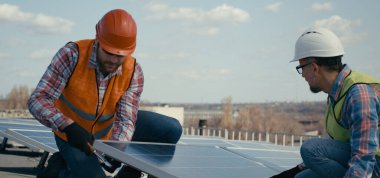 Güneş panellerini metal standına kuran teknisyenler