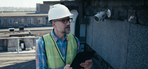 Mérnök ellenőrzi a biztonsági kamera táblagéppel — Stock Fotó