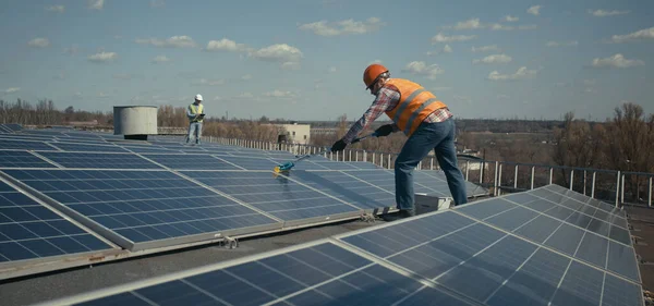 Técnico de limpeza de painéis solares no telhado plano — Fotografia de Stock