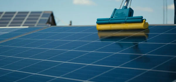 Techniker reinigt Sonnenkollektoren auf Flachdach — Stockfoto