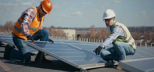 Technicy instalujący panele słoneczne na metalowym stojaku — Zdjęcie stockowe