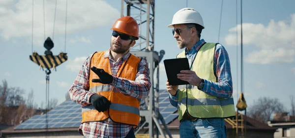 Ingénieur et technicien discutant entre panneaux solaires — Photo