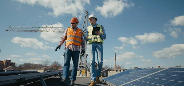 Ingénieur et technicien discutant entre panneaux solaires — Photo