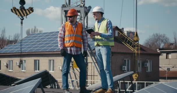 Engenheiro e técnico discutindo entre painéis solares — Vídeo de Stock