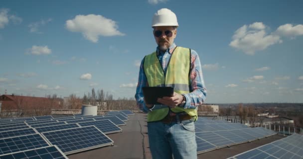 Inżynier korzystający z tabletu pomiędzy panelami słonecznymi — Wideo stockowe