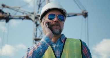 İnşaat alanında telefonla çalışan bir mühendis.