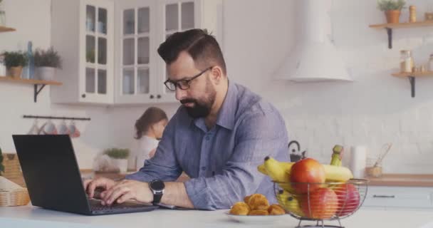 Hombre trabajando en su portátil en la cocina — Vídeo de stock