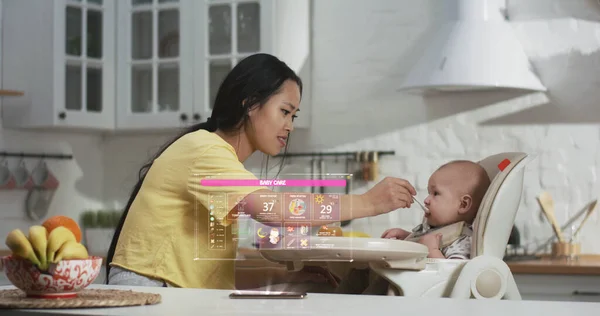 Mãe alimentando bebê na cozinha — Fotografia de Stock