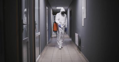 Men in hazmat suits disinfecting building clipart