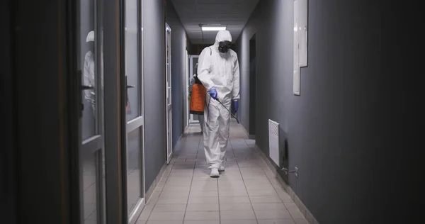 穿着防腐衣的男人在大楼里消毒 — 图库照片