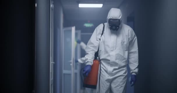 Hombres con trajes de materiales peligrosos desinfectando el edificio — Vídeo de stock