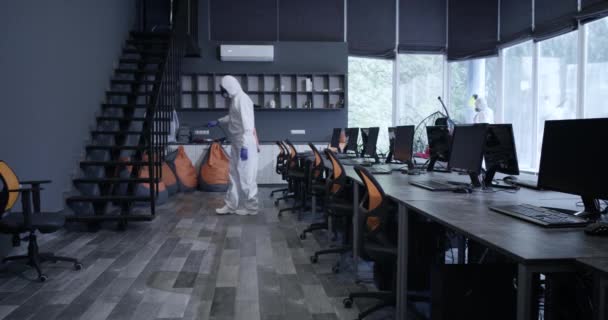 Mężczyźni w kombinezonach dezynfekujących biuro — Wideo stockowe