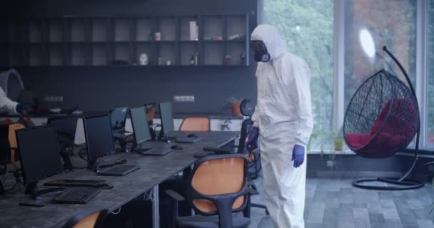 Мужчины в защитных костюмах дезинфицируют офис — стоковое видео