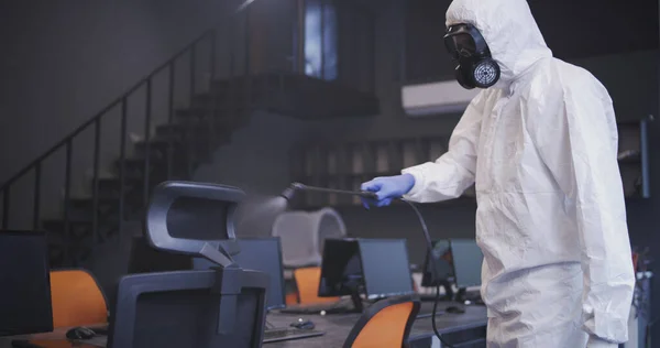 Hombres con trajes de materiales peligrosos desinfectando la oficina — Foto de Stock