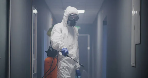 Hombres con trajes de materiales peligrosos desinfectando el edificio —  Fotos de Stock