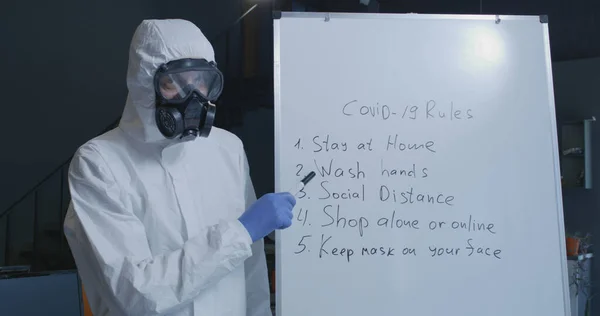 Man is hazmat suit presenting Covid-19 rules — Stock Photo, Image