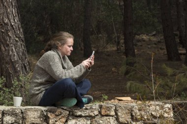Ormandaki kadın tablete bakıyor.