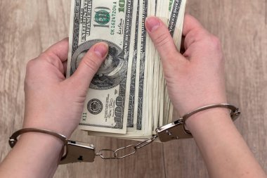 female hands in handcuffs with dollars on the table clipart