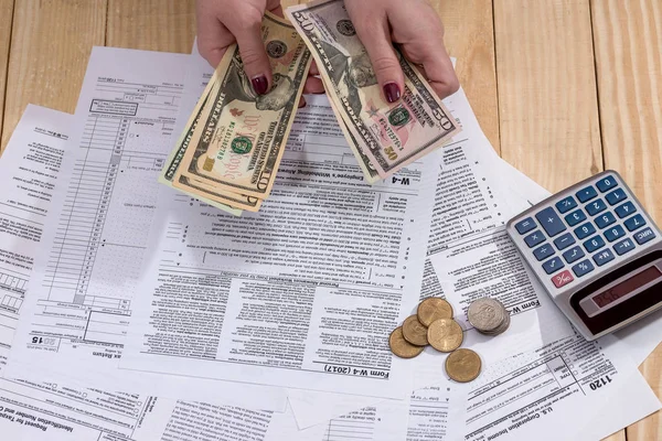 a woman writes a tax return 1120 on a wooden table