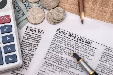 vergi formu w4 kalem ve ABD Doları, hesap makinesi ve kalem ile.