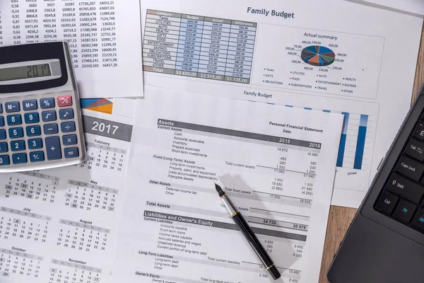 Financial charts, graphs, diagrams, financial report, computer and pen on wooden desk.