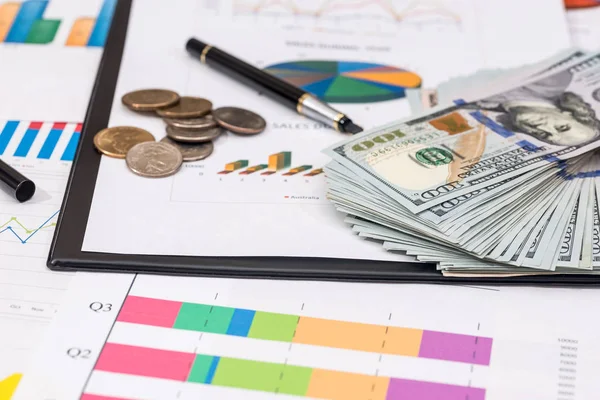 para, sikke üzerinde hisse senedi grafiği, hesap makinesi ve kalem.