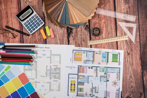 house floor paper plan and wooden sampler, work tolls, calculator on wooden table.