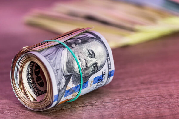 долларовый рулон на деревянном столе
